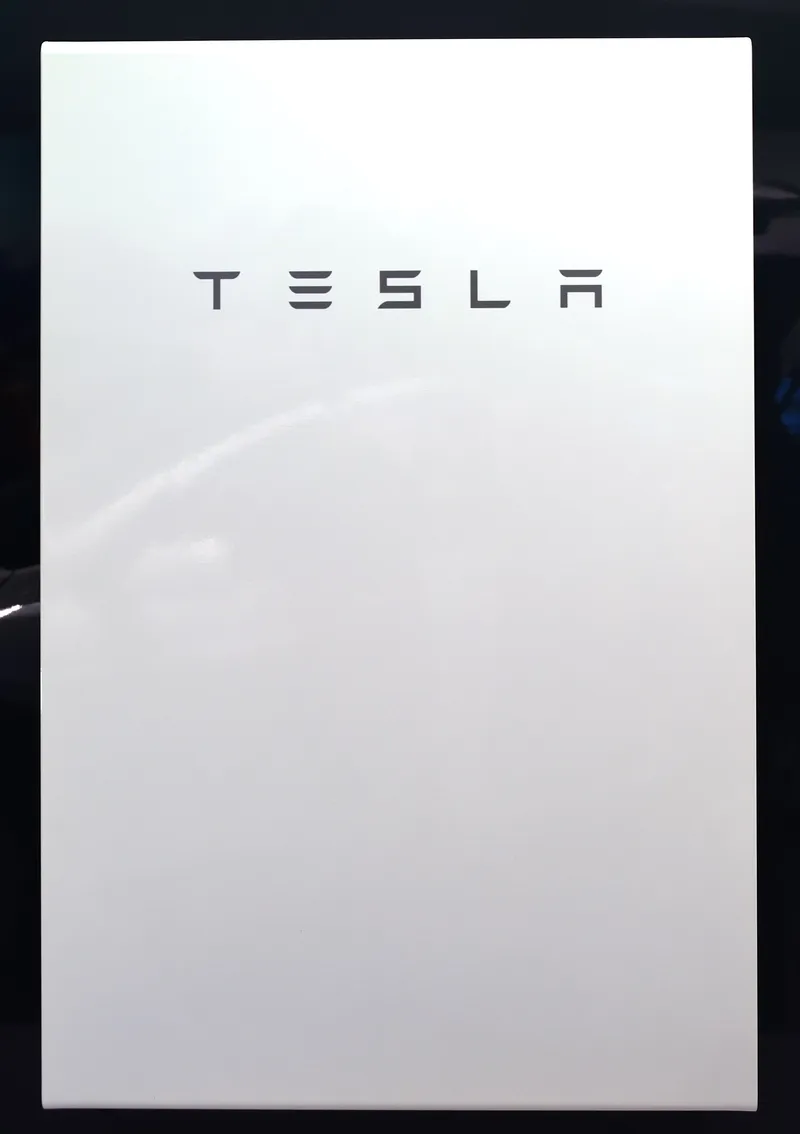 Front view of a white Tesla Powerwall home battery with the Tesla logo.