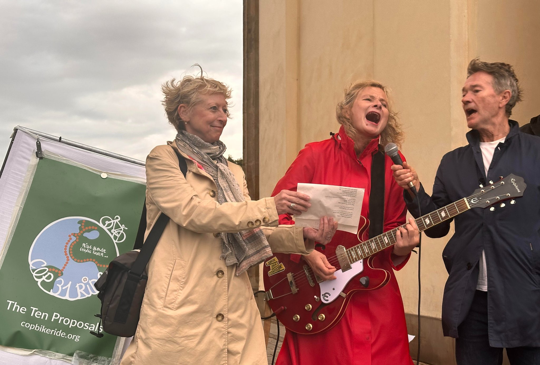 German pop singer/song writer Bernadette La Hengst with Chor der Statistik members Birgit Herrgoss and Nick Nuttall welcome the cyclists with her climate hit "I Need Air" first performed in 2018 at the Climate COP in Katowice, Poland