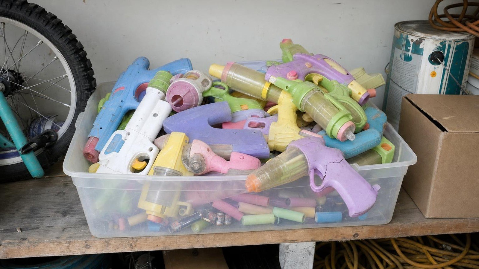 A garage tub full of cheap, worn foam dart blasters and dead batteries