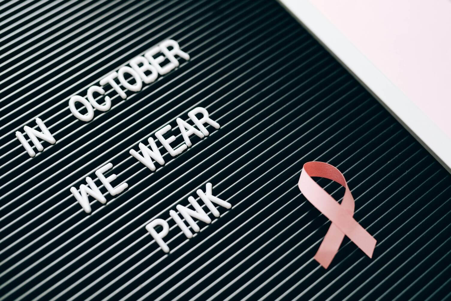 blackboard sign, “in october we wear pink” with a pink ribbon