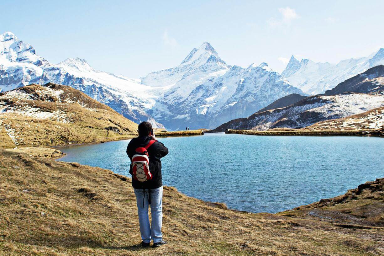 man taking a photo in front of a mountain