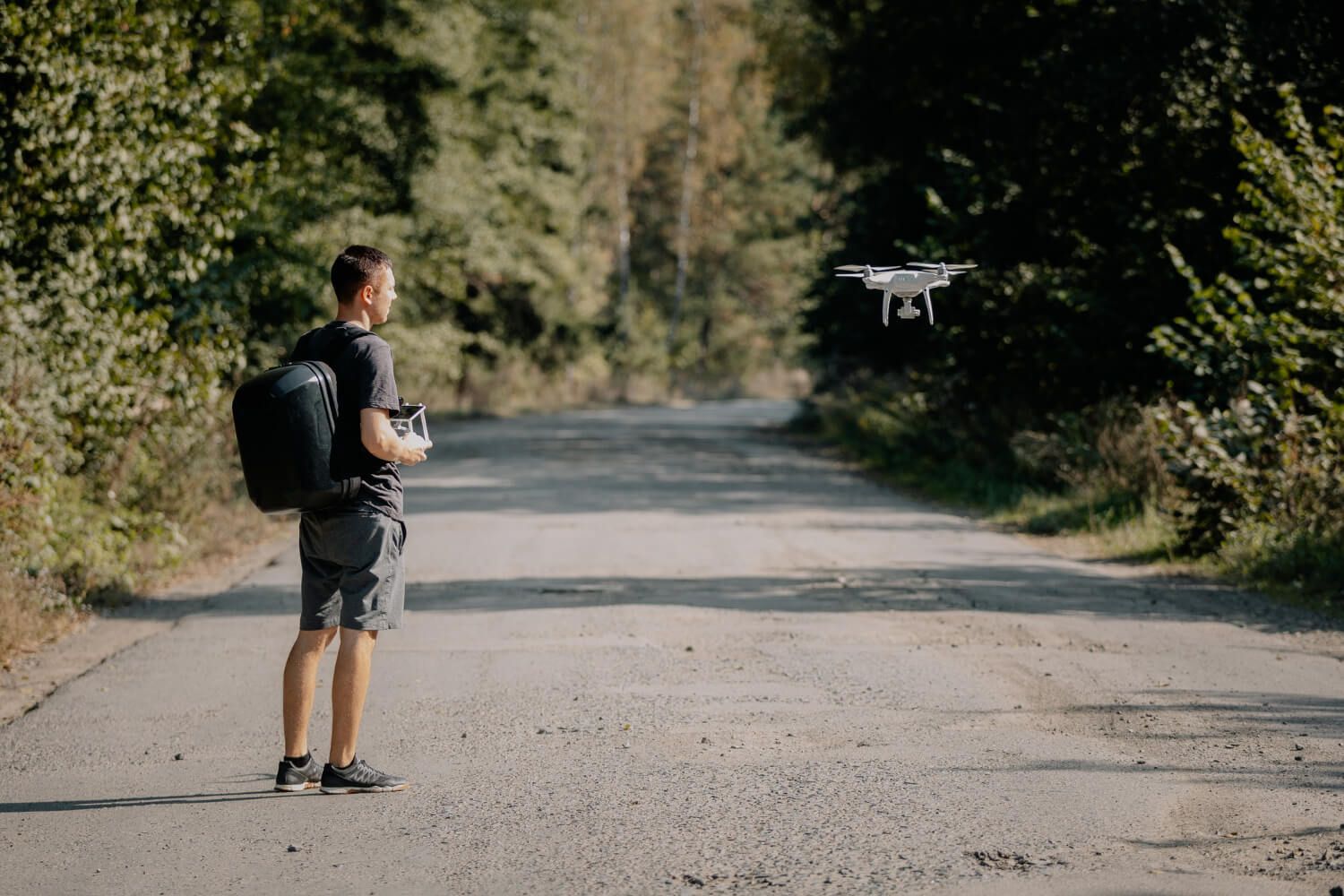 A compact drone placed next to a backpack, illustrating its portability