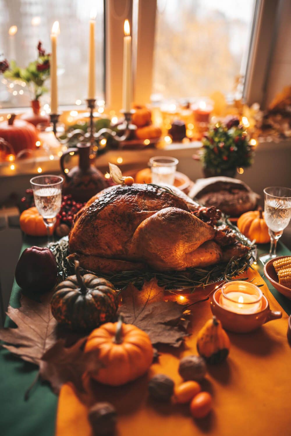 A festive Thanksgiving table setting with candles, pumpkins, and a golden turkey centerpiece.