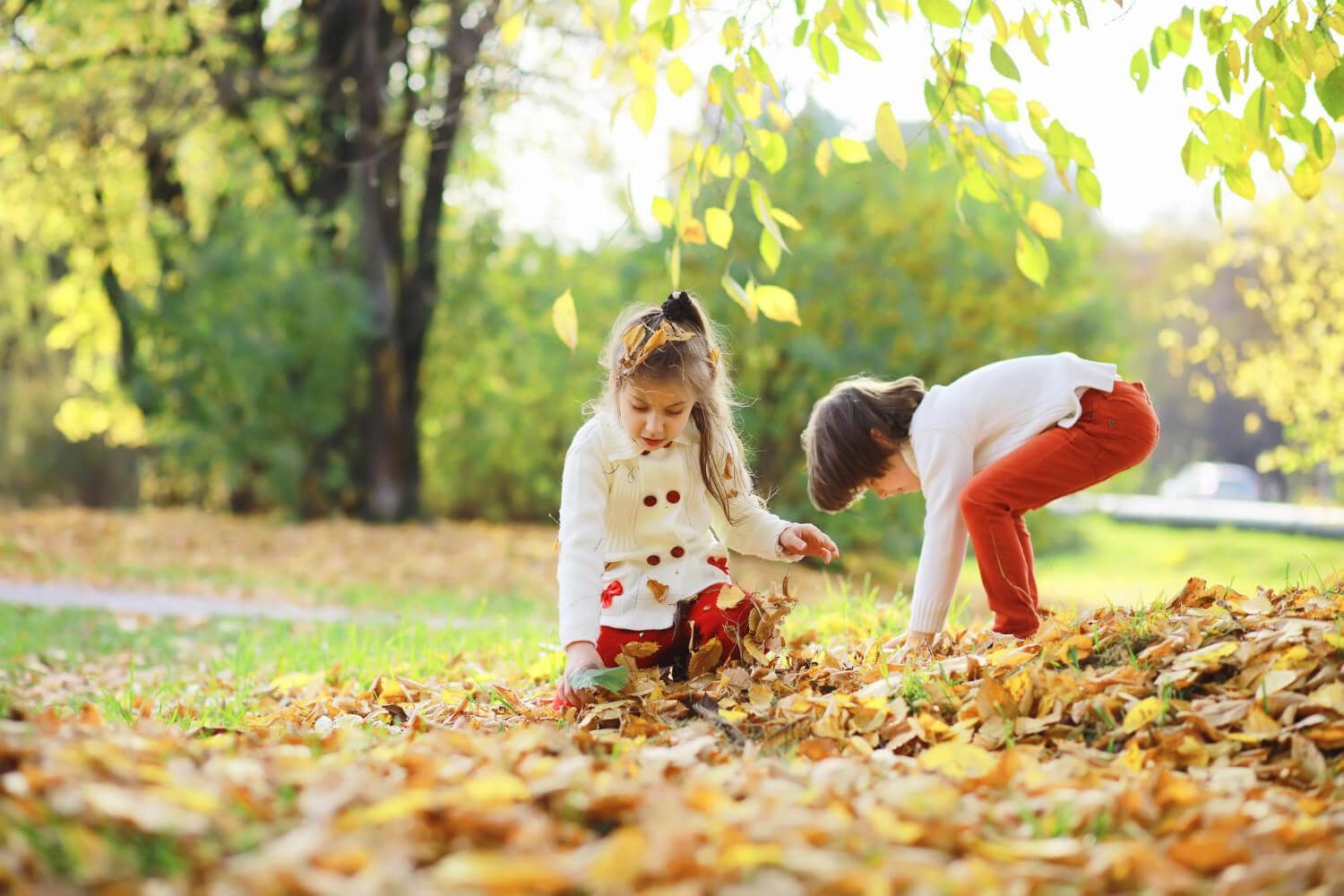 Children playing with autumn leaves in the yard