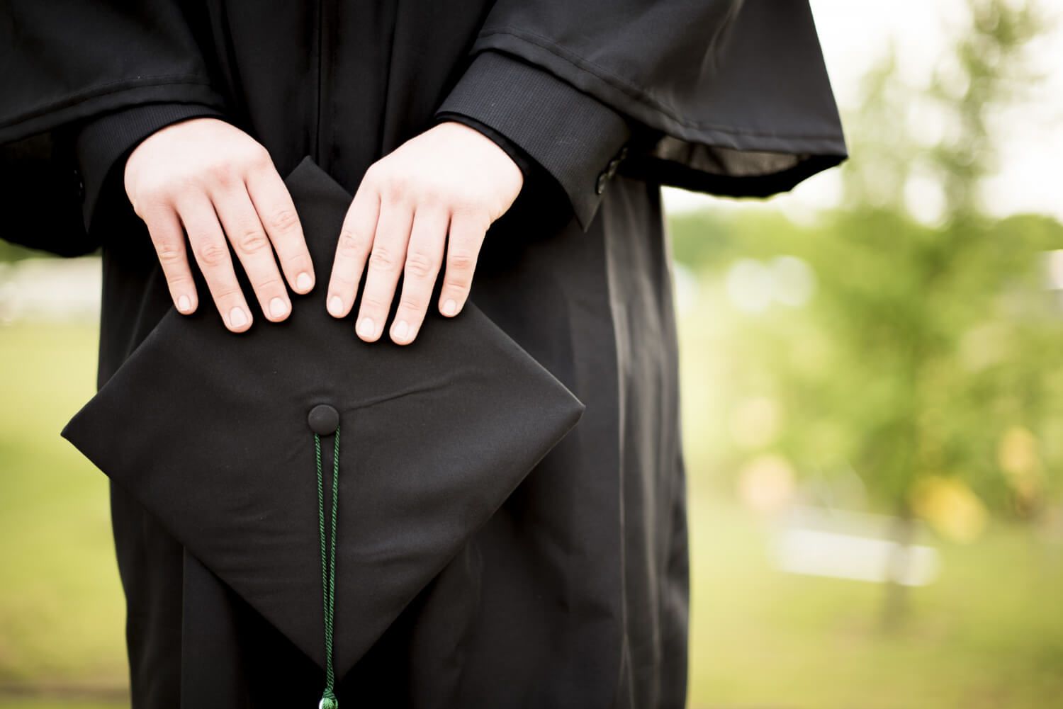 Hands fixing tassel onto a graduation cap button