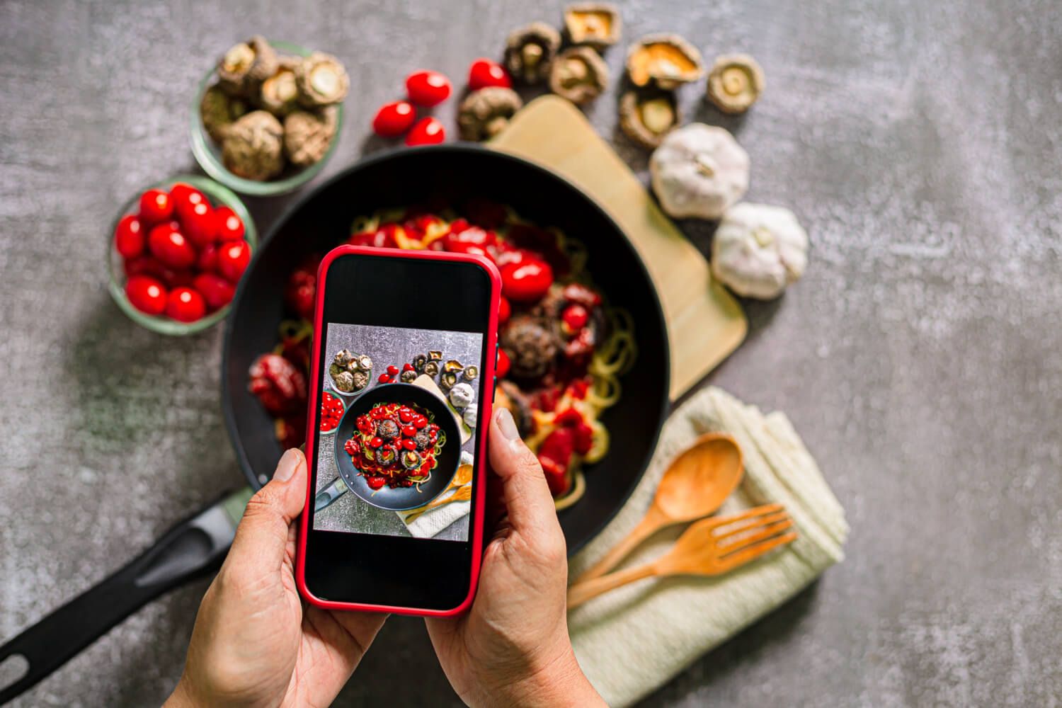 Hands holding an iPhone upside down capturing a head-on shot of a plate of food