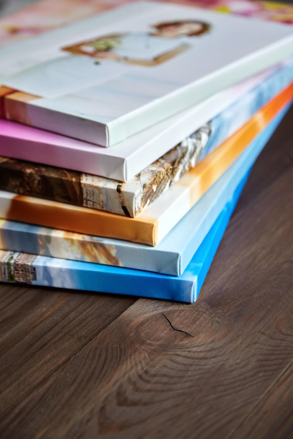 Stack of glossy photo prints in various sizes on a wooden surface.jpg