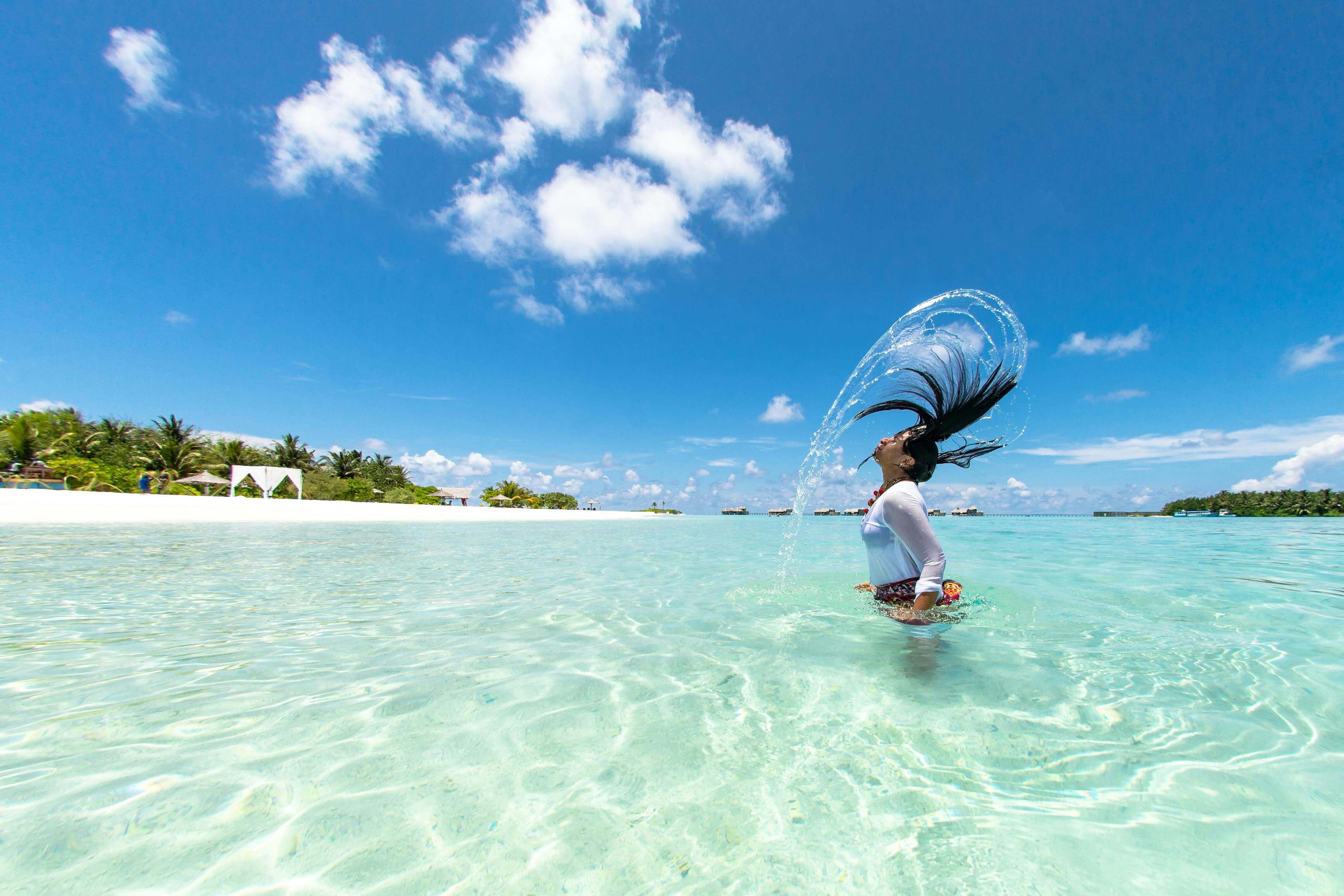 woman flipping her hair in blue, tropical water