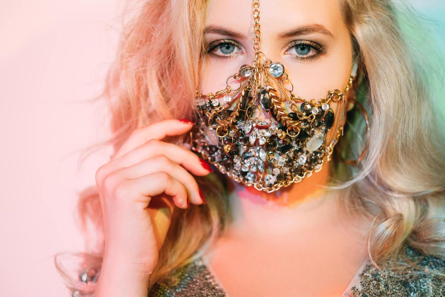 a girl with blue eyes who wears a shiny mask made of diamonds