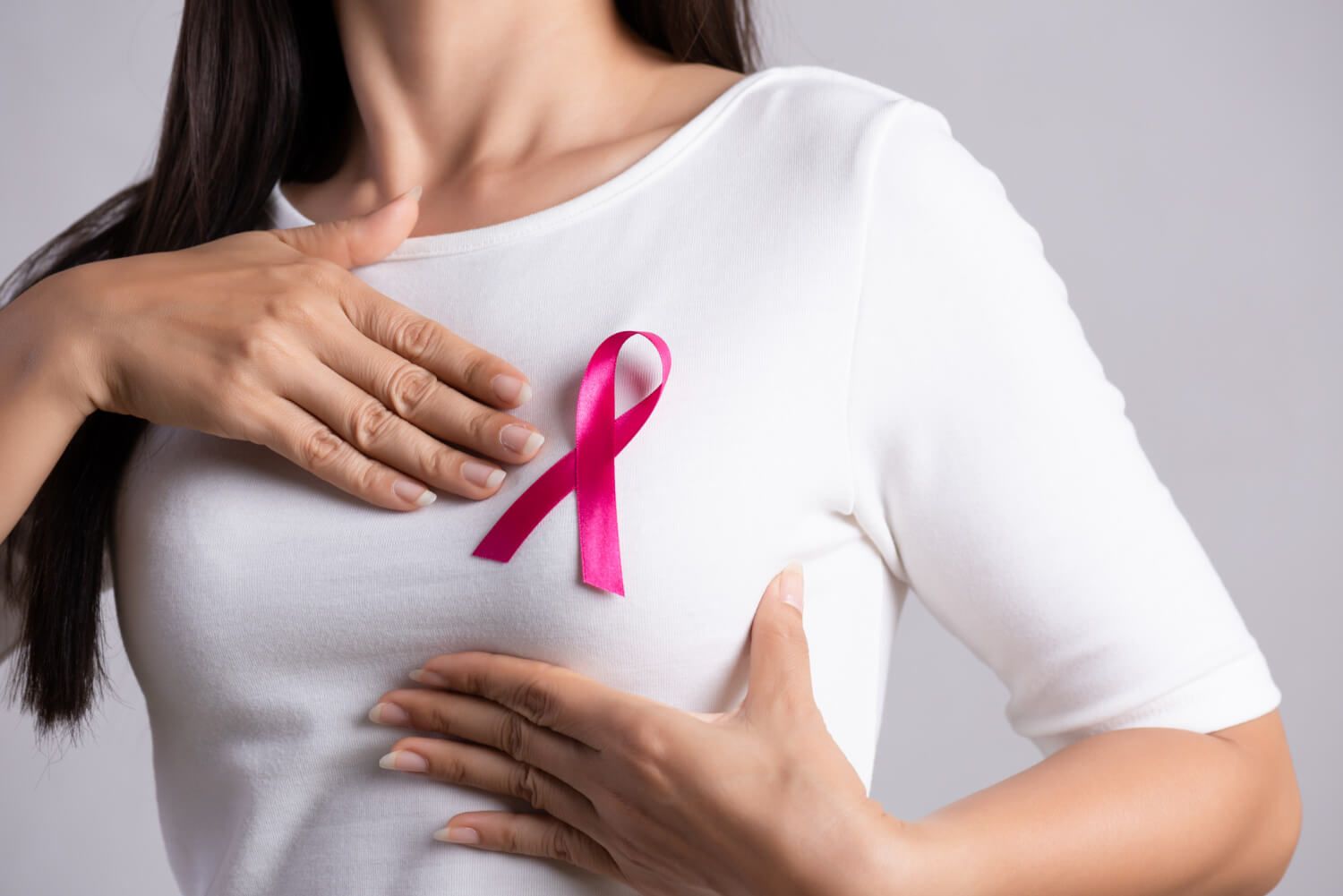 a young woman in a white jacket with a distinctive symbol on her chest - a ribbon symbolizing the fight against breast cancer