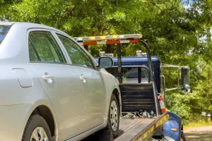 Beige Toyota with auto breakdown insurance being loaded on a tow truck