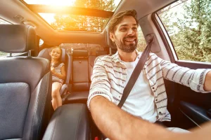 Dad and daughter in a car with inclusionary warranty coverage on a beautiful sunny evening