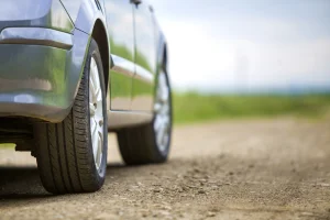 Close up of wheels and tires on a vehicle with a service contract sitting on a dirt road