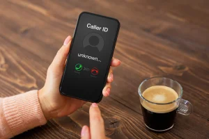 woman drinking coffee getting a warranty robocall on her iphone