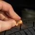 Driver performing a penny test on a tire to determine tread depth