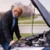 Man standing in front of a broken down car with the hood open