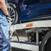 Tow truck driver loading a blue car with auto breakdown protection on the back of a flat bed tow truck