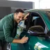 man standing next to his green car which is covered under an auto protection plan