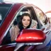 Woman sitting in a red car with a budget car warranty holding money and a car key