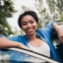 Happy young woman with beautiful smile standing beside her car with a car service contract