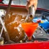Mechanic pouring oil into a car engine using a funnel
