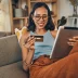 Smiling woman using credit card to buy a direct buy auto warranty on digital tablet at home