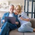 older couple on sofa with a computer getting a car refinance and warranty quote online