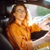 woman in orange shirt driving a car that is covered by an extended warranty