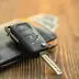 Car key on top of a wallet on a wooden table