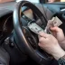 Man counting hundred dollar bills in car