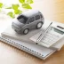 Grey toy car and a calculator on a desk