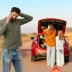 Man with powertrain warranty coverage on a cell phone in front of a broken down car red car with family on the way to vacation