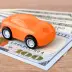 Orange toy car on stack of $100 bills