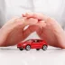 Red toy car shielded by interlocked hands representing a vsc car warranty