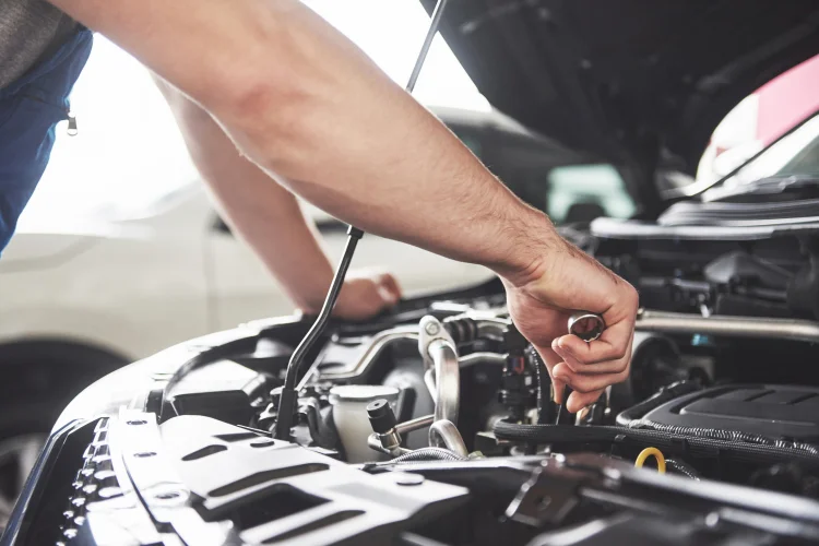 Close up hands of a mechanic doing maintenance on a car with an affordable car service contract