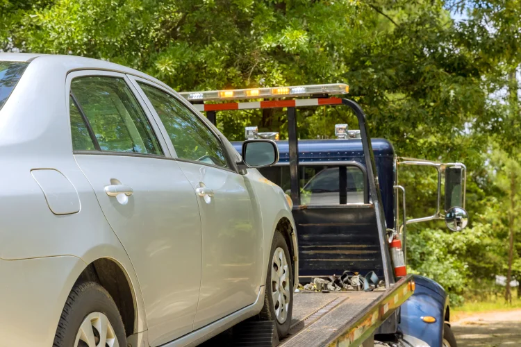 Beige Toyota with auto breakdown insurance being loaded on a tow truck