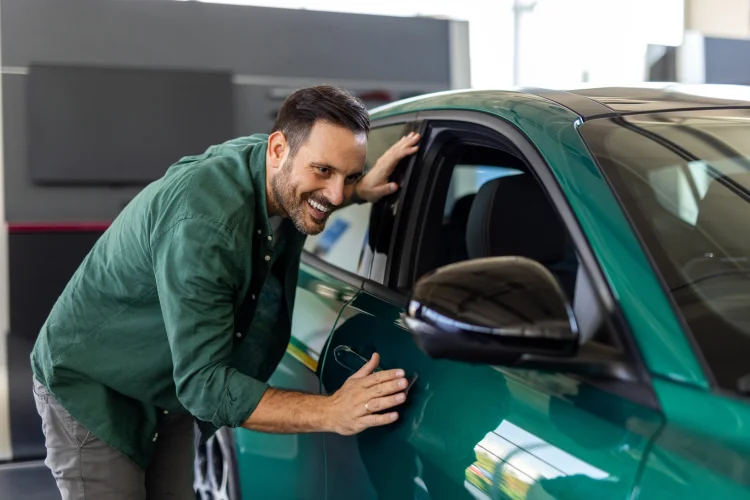 man standing next to his green car which is covered under an auto protection plan