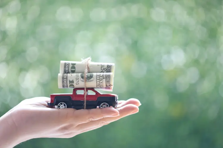 Toy car in raised palm with money on top
