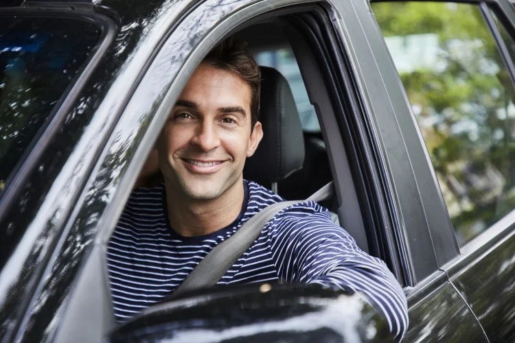 Happy male driver in a car who bought an auto warranty direct from Cuvrd