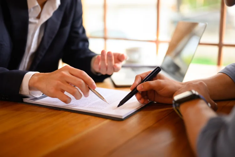 insurance agent pointing at contract showing client where to signature sign