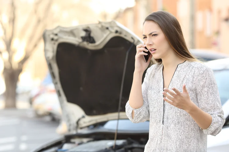 Upset woman calling insurance on phone after car breakdown on the street