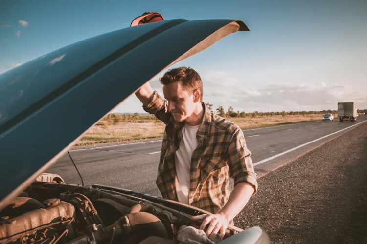 Man in plaid shirt broken down on the side of the road with hood open and in need of car fix insurance