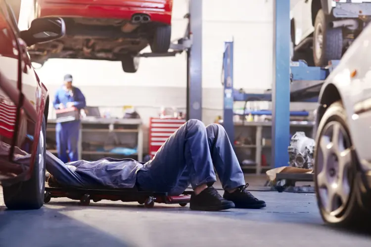 mechanic under car performing routine maintenance