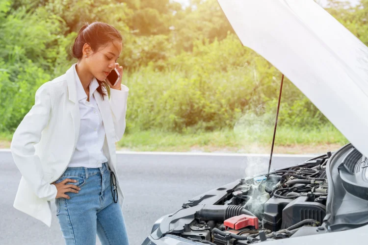 Woman stranded on the side of the road calling a tow truck after her car overheated