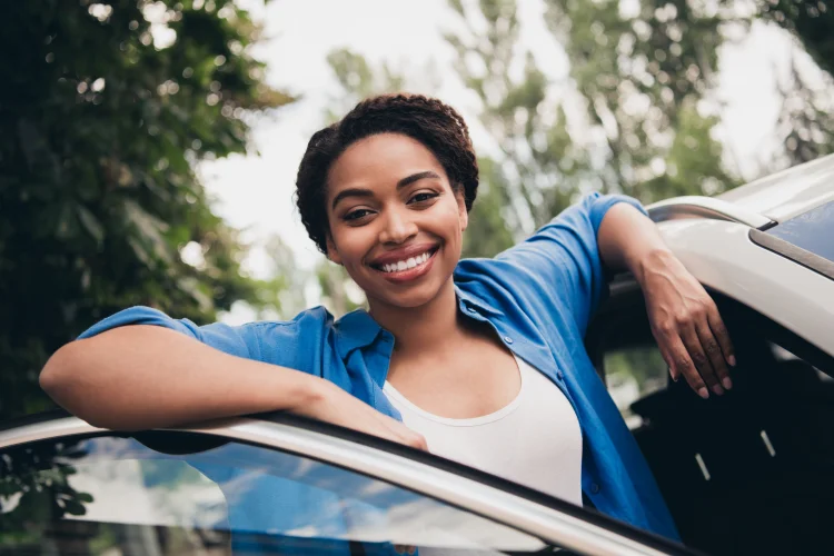 Happy young woman with beautiful smile standing beside her car with a car service contract