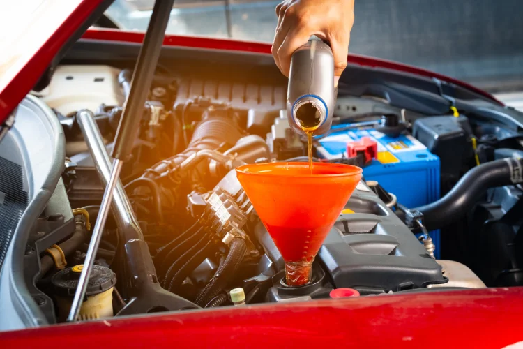 Mechanic pouring oil into a car engine using a funnel