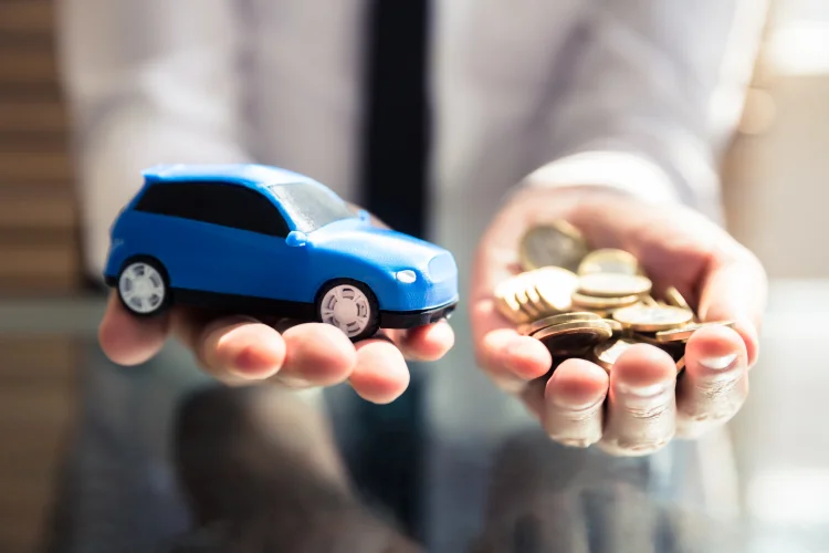 closeup of hands holding a blue toy car and gold coins