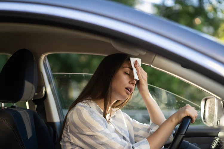 Girl driver being hot during heat wave in car, sweating because of high humidity