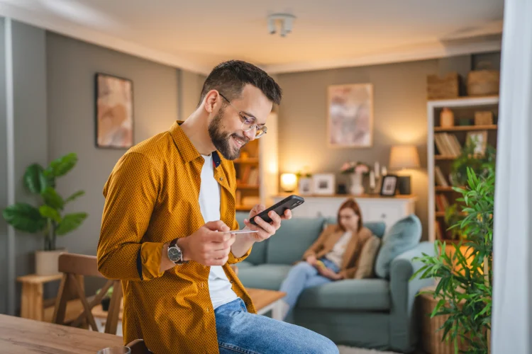 Man buying a direct-to-consumer auto warranty on his phone with his spouse looking on
