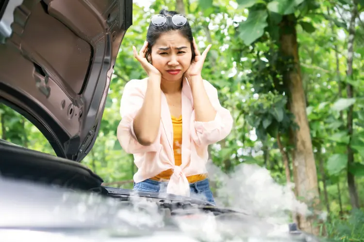Woman in trouble with broken, overheating car with smoke from damaged engine